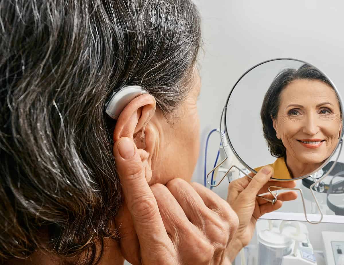 woman with hearing aid smiling in mirror